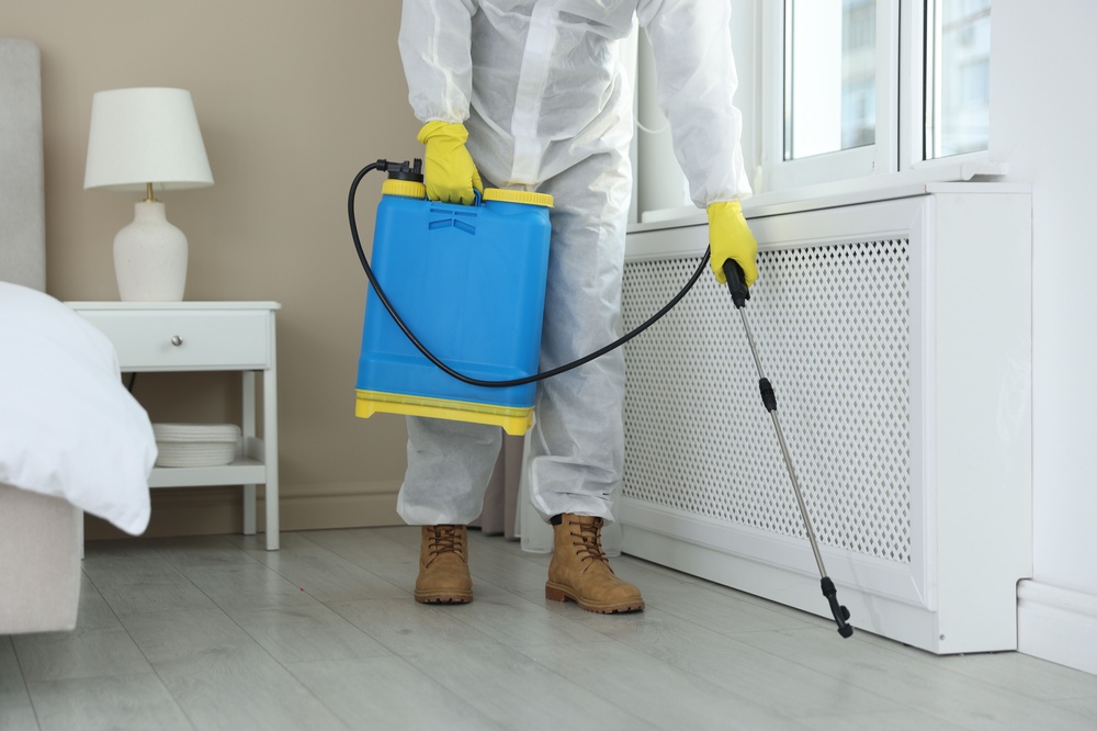 A technician servicing the baseboards around a bedroom.
